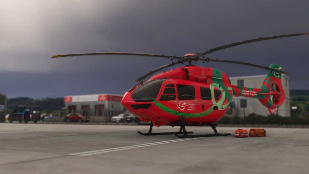 Burning Blue Design's Welshpool airport for MSFS 2020 and MSFS 2024, insim view of Welsh Air Ambulance EC-145 helicpoter on the apron with EMT bags ready to load in. 