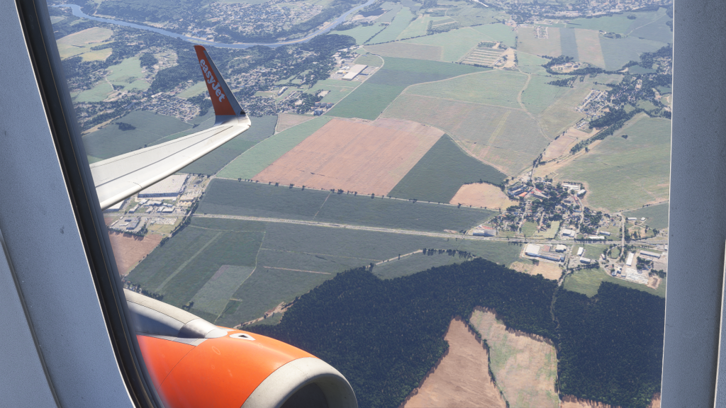 In Sim view of FENIX's A320 with winglets in EasyJet livery. Passenger window view of the wing and engine at low altitude over the countryside.