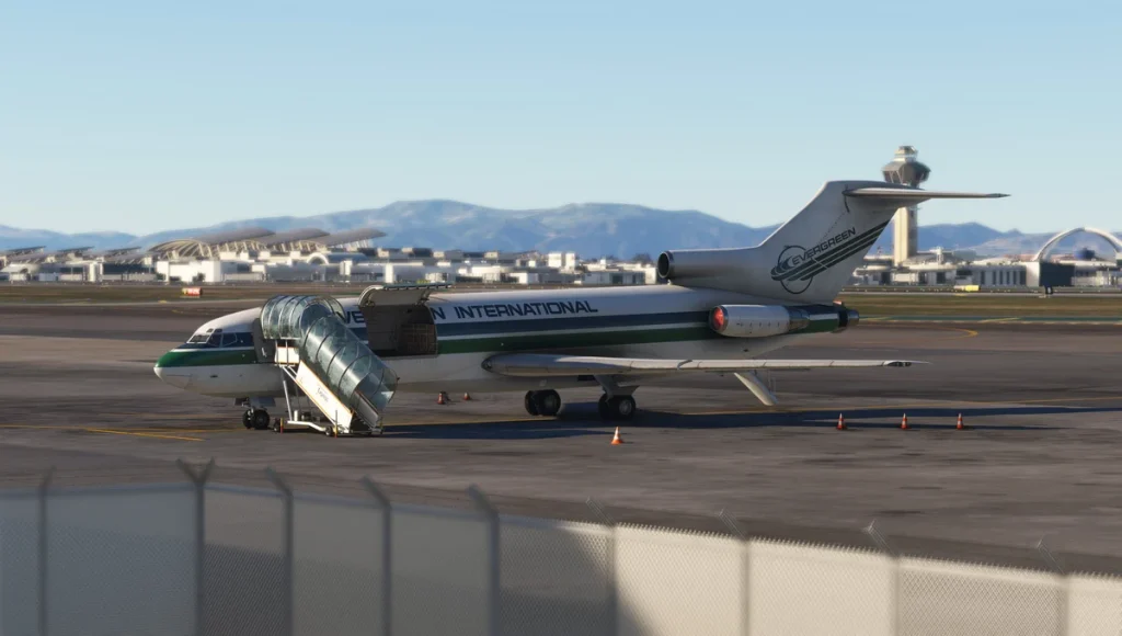 Evergreen International Boeing 727 parked on airport tarmac with mobile stairway and terminal buildings in the background