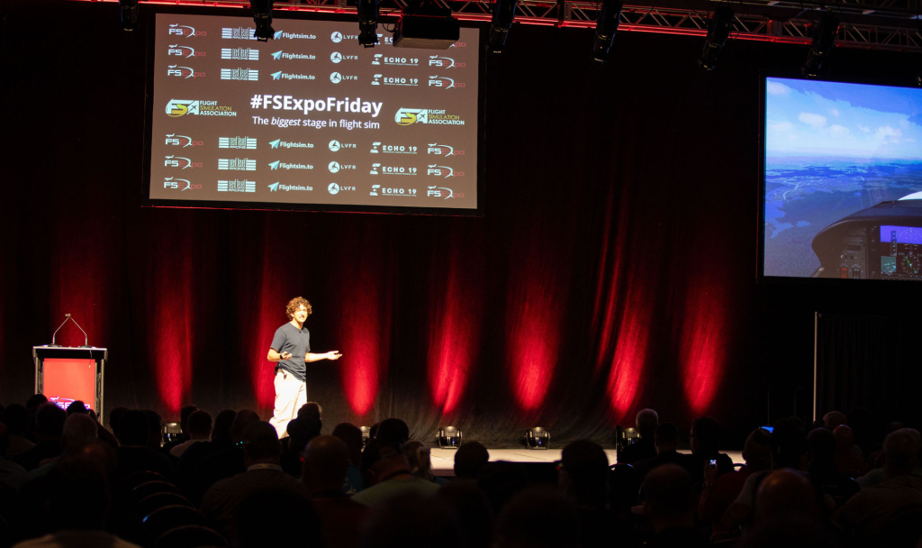 Presenter speaking on stage during a FlightSimExpo seminar session