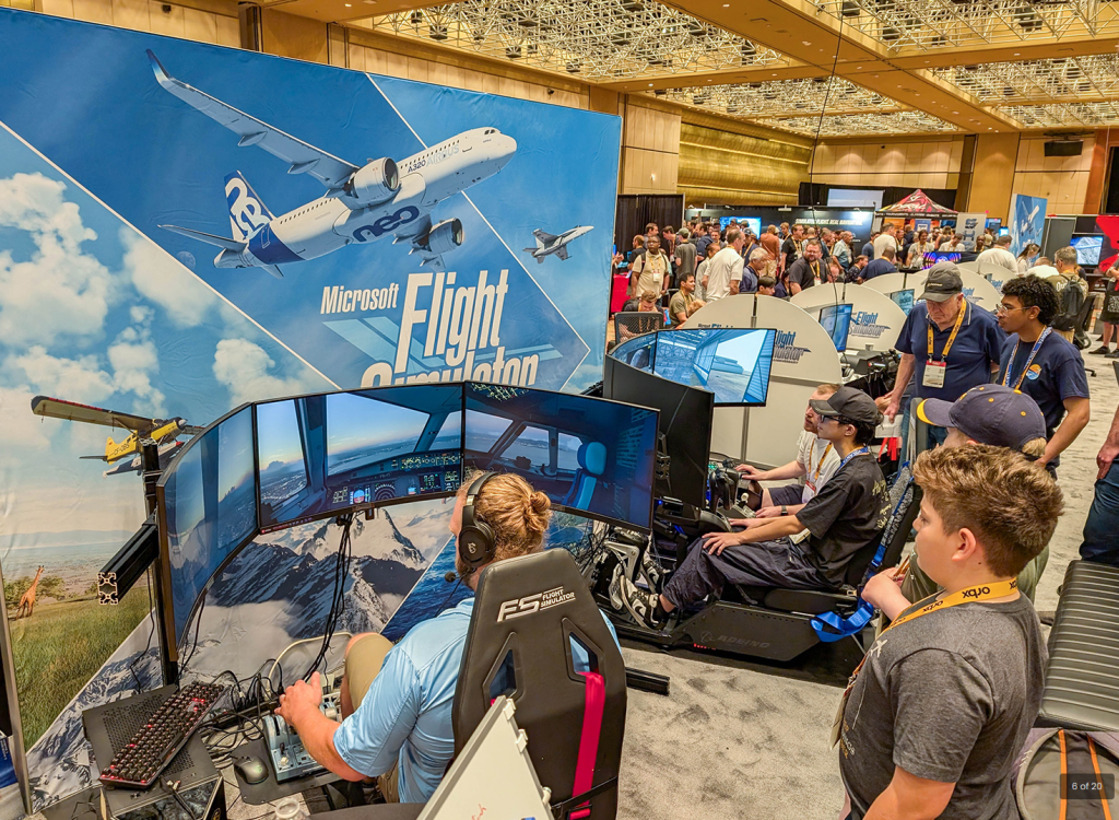 Attendees testing flight simulator setups inside the FlightSimExpo exhibit hall