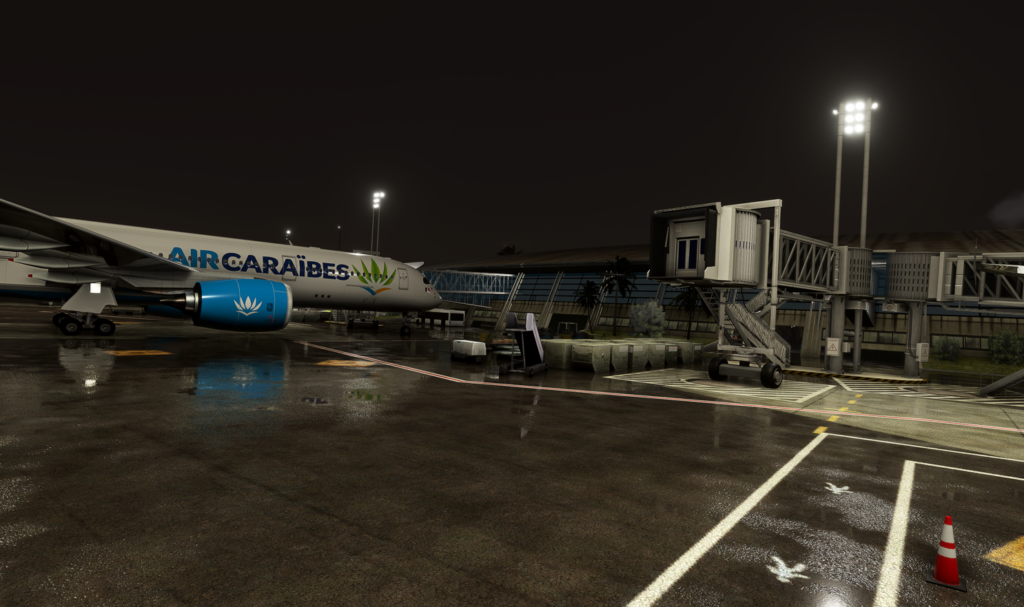 Night view of an Air Cara&iuml;bes jet at Martinique Aim&eacute; C&eacute;saire International Airport, with wet apron and terminal lights