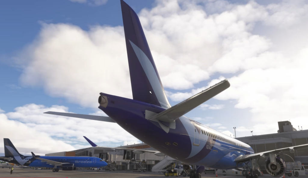 Rear view of the Synaptic A220-300 alongside Breeze Airways aircraft at the terminal.