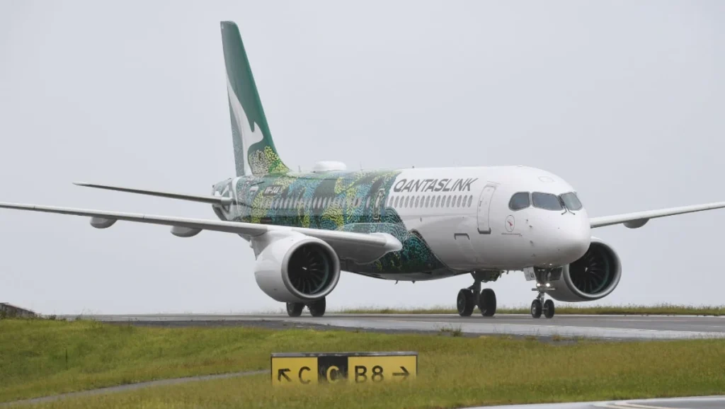 QantasLink Airbus A220-300 in Indigenous Australian special livery taxiing on a wet runway