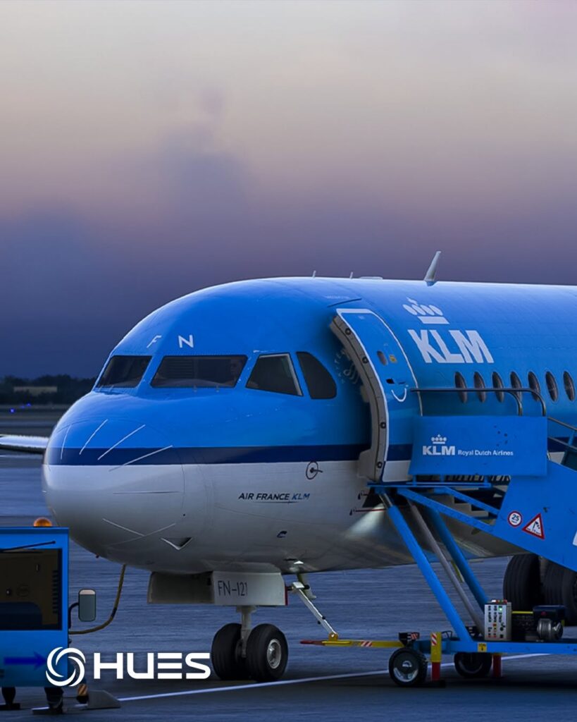 Image of Fokker F100 in KLM livery parked at an airport with service equipment attached.